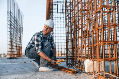 Paslı metal nesnelerle. Gündüz vakti inşaatta çalışan bir adam var..