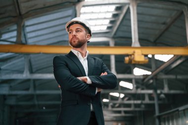 Fabrikada resmi giyinmiş ciddi bir yönetici var..