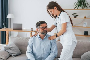 Olgun bir adamla çalışmak. Ofiste beyaz önlüklü profesyonel hemşire var..