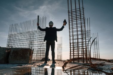 Ellerini kaldır. Akşam vakti ayakta. İnşaat alanında resmi kıyafetli bir işadamı var..