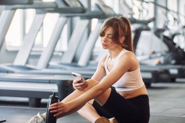 Akıllı telefon sizin ellerinizde. Spor elbiseli genç bir kadın spor salonunda spor yapıyor..