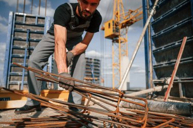 Pas kaplı metal parçaları. Üniformalı adam inşaat alanında çalışıyor..