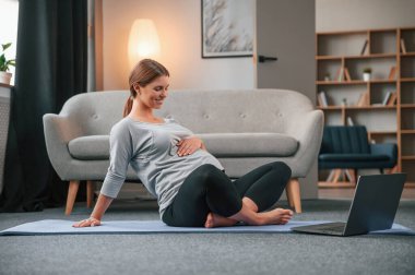Laptop kullanarak yoga dersleri alıyorum. Güzel hamile kadın evde..