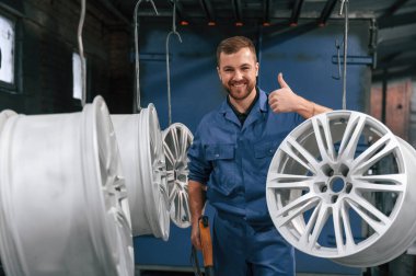 Başparmağımı gösteriyorum. Araç servis istasyonu çalışanı tekerlek diskleriyle ilgileniyor..