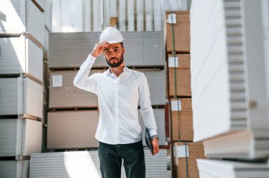 Resmi kıyafetlerle. Depo işçisi depoda bir sürü ürünle birlikte..