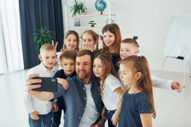 Making a selfie by phone. Group of children students in class at school with teacher.