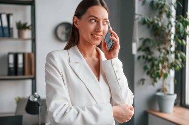 Telefonla konuşuyorum. Resmi giyinmiş güzel bir kadın ofiste çalışıyor..