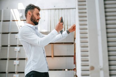 Tablet tutuluyor ve verileri kontrol ediliyor. Depo işçisi depoda bir sürü ürünle birlikte..