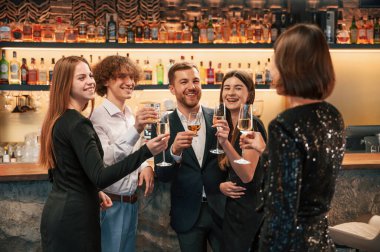 Konuşmak, gülümsemek, eğlenmek. Güzel giyinmiş bir grup insan içeride yeni yılı kutluyorlar..