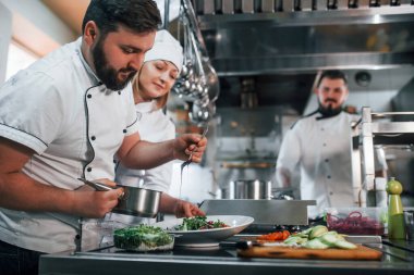 Üç kişi. Vejetaryen salatası. Profesyonel aşçı mutfakta yemek hazırlıyor..