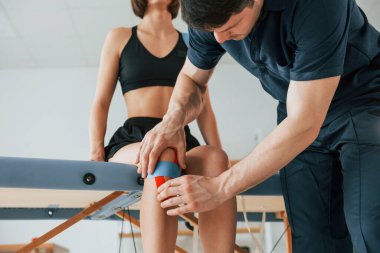 Bacakları bitirmek üzereyim. Cilde Kinesio bandı yapıştıran bir kadın fizyolog..