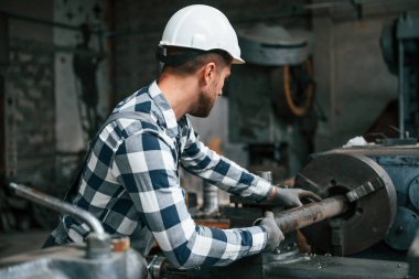 Endüstri makinesini manipüle etmek. Üniformalı fabrika çalışanı içeride..