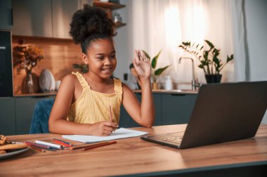 Çevrimiçi çalışma. Gündüz vakti evde rahat giyinen sevimli siyah kız var..