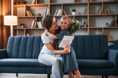 Birbirinize sarılın. Hediyeyi veriyorum. Genç anne kızıyla birlikte dairede..