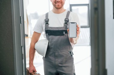 Elinde akıllı telefonla. Tamirci modern odada kapalı duruyor..