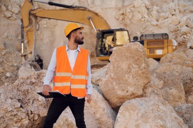 Kayalar ve kazıcı. Üniformalı adam gündüz taş ocağında çalışıyor..