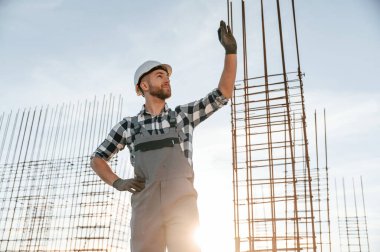 İnşaat alanında. Gri üniformalı adam çalışıyor..