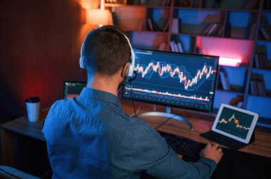 Hisse senedi tüccarı kapalı alanda bilgisayar başında çalışıyor. Değişim ve para kavramı.