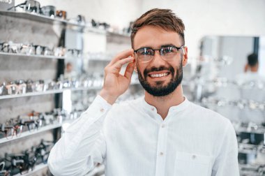 Neşeli bir ruh hali. Optik mağazasından gözlük seçen sakallı şık bir adam..