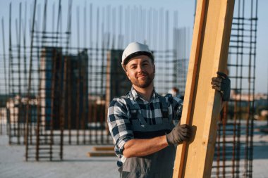 Durup poz vermek. Gündüz vakti inşaatta çalışan bir adam var..