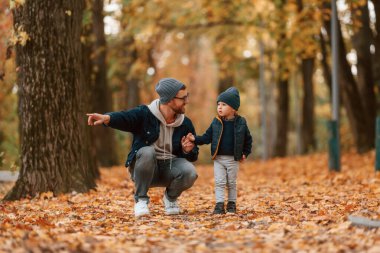 Babamın elinde bir şey var. Baba ve küçük oğlu gündüz vakti dışarıda beraberler..