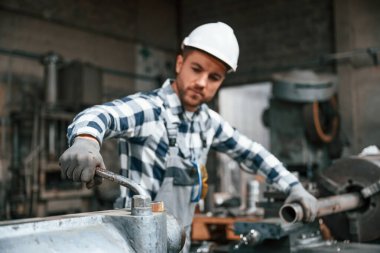 Üniformalı fabrika çalışanı içeride. Endüstri makinesiyle.