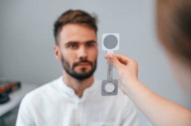 Tutma aleti. Özel optometrist cihaz kullanarak klinikteki kadın doktor tarafından erkeğin görüşü kontrol edildi..