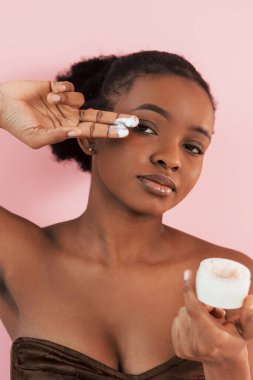 Temiz deri döllenmesi. Pembe arka plana karşı olan Afrikalı Amerikalı genç bir kadının portresi.