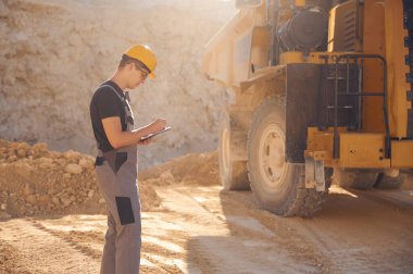 Nakliye kamyonunun yanındaki belgelerle birlikte. Üniformalı adam gündüz taş ocağında çalışıyor..