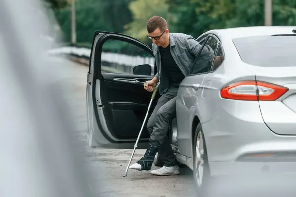 stock image Injured man with crutches is going out from the car.