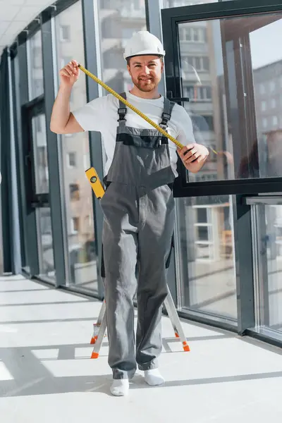 stock image Holding measure tape. Repairman is working indoors in the modern room.