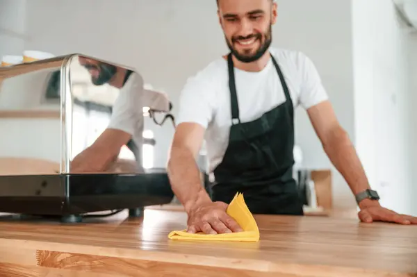 stock image Cleaning table. Cafe worker in white shirt and black apron is indoors.