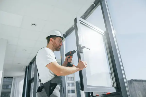 stock image Using the drill. Repairman is working indoors in the modern room.