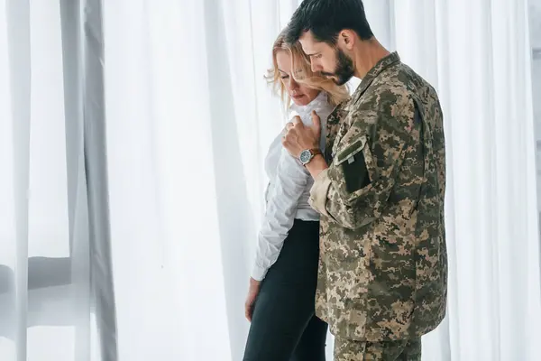 stock image Soldier with his wife standing indoors and embracing.