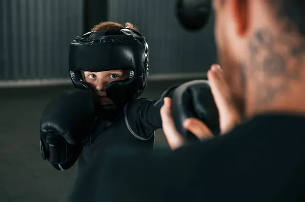 stock image Doing some punches. Coach is teaching the boy box techniques indoors.