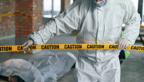 Держу кассету с предупреждением. Детективы собирают улики на месте преступления рядом с трупом.