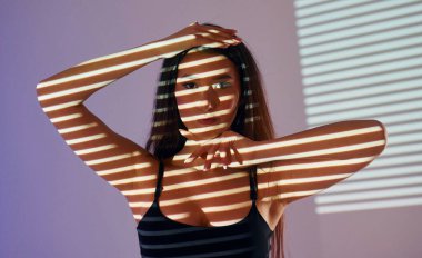 Projektör ışıklarının önünde duruyor. Güzel genç bayan stüdyoda..