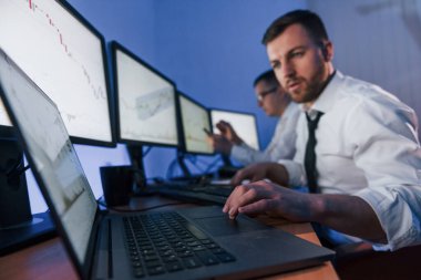 Kâr etmek için modern teknolojiyi kullanmak. Ofiste değişim teknolojisiyle çalışan iki borsacı..