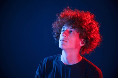 Yukarı bakıyorum. Kıvırcık saçlı genç adam kapalı alanda neon ışıkla aydınlatılır..