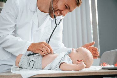 Manzarayı kapat. Steteskop kullanıyorum. Beyaz önlüklü doktor içeride küçük bebekle ilgileniyor..