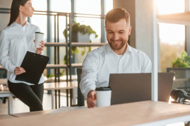 Güzel güneş ışığı. Erkek ve kadın modern ofiste birlikte çalışıyorlar..