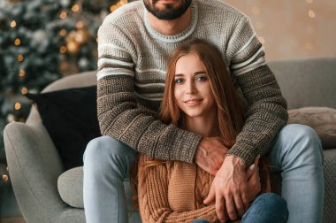Oturup ileriye bakıyoruz. Güzel genç çift yeni yılı evde kutluyor..
