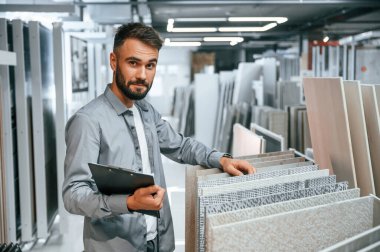 Elinde not defteriyle dikiliyorsun. Tarz sahibi güzel adam ev için malzeme deposunda..