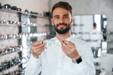 Büyük seçim. Optik mağazasından gözlük seçen sakallı şık bir adam..