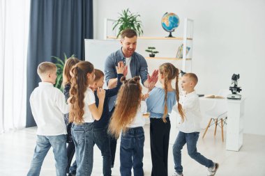 Çak bir beşlik hareketi. Okulda öğretmenle birlikte bir grup çocuk öğrenci..