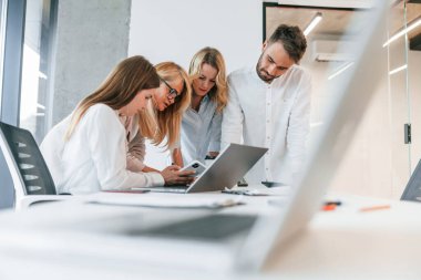 Birlikte dizüstü bilgisayarla çalışıyoruz. Profesyonel iş adamlarından oluşan bir grup ofiste..