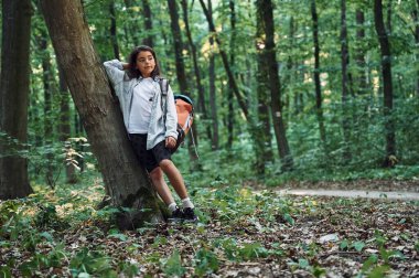 Ağaca yaslanarak. Kız yaz günü ormanda yeni yerler keşfediyor..