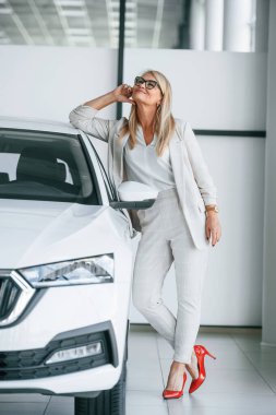 Arabaya yaslanarak. Beyaz elbiseli kadın araba galerisinde..
