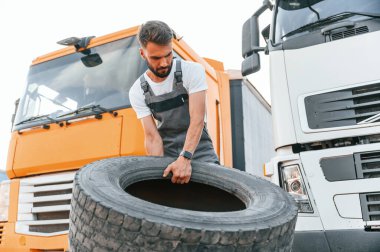 Patlak lastiği hareket ettiriyorum. Üniformalı bir adam büyük bir kamyon için hizmet veriyor..