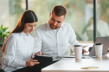 Fikirlerimizi paylaşıyoruz. Erkek ve kadın modern ofiste birlikte çalışıyorlar..